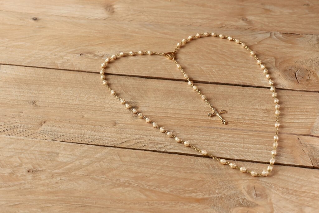 Golden rosary with cross arranged on a natural wooden table, symbolizing faith and spirituality.